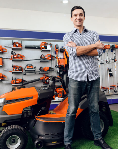 A man is standing near a lawn mower.